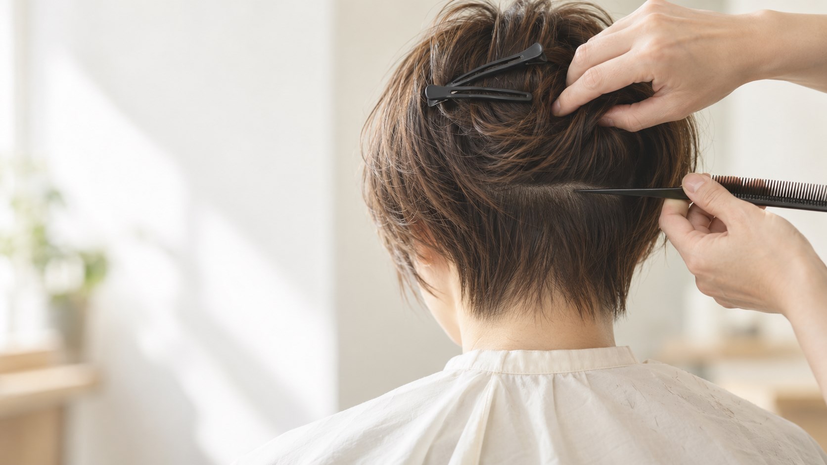 少し伸びたショートヘアの襟足を、美容師がコームで分け取って確かめている